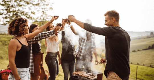 Group of adults raising their glasses to cheers outside