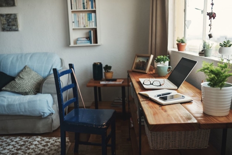 home office in front of window with blue chair, laptop, and notebook